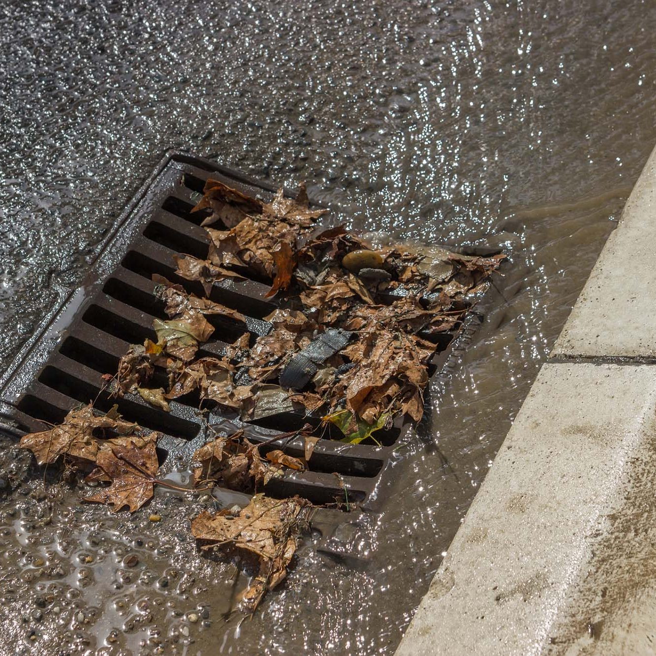 Melted water flows down through the manhole cover on a sunny spring day